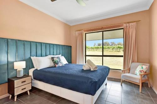 a bedroom with a bed and a window and a chair at The Lodge - Ironstone Estate Hunter Valley in Lovedale