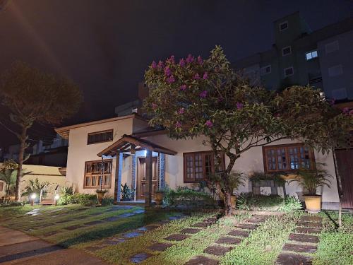 una casa con un árbol delante de ella por la noche en Suítes Jardim dos Sonhos, en Ubatuba