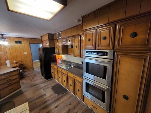 una cocina con armarios de madera y electrodomésticos de acero inoxidable en Sits on an acre near Grace land with 3 full baths en Memphis