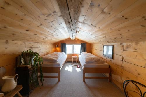a room with two beds in a wooden cabin at Nuessli in Wildhaus