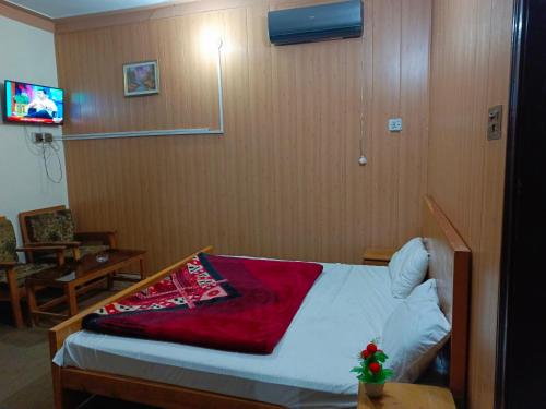 um quarto com uma cama com um cobertor vermelho em SEE MOTEL em Muzaffarabad