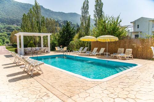 una piscina con sillas y sombrillas en un patio trasero en Villa Martini en Vátos