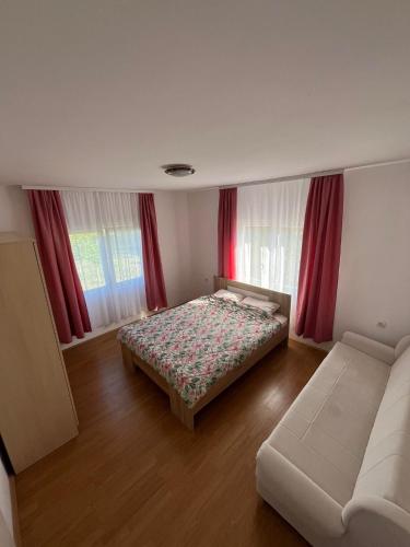 a bedroom with a bed and a couch and windows at Vikendica Lazic in Ljubovija
