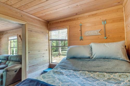 a bed in a log cabin with a window at Quiet Hemphill Cabin Retreat Near Toledo Bend Lake in Hemphill