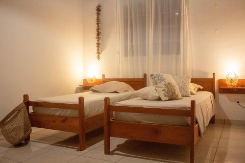 two twin beds in a bedroom with two candles at Ô'Bèl Ter in Pointe-Noire