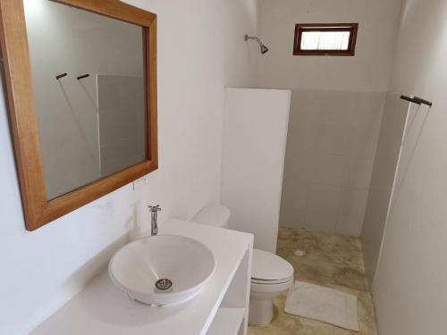 een badkamer met een wastafel, een toilet en een spiegel bij Sierra Sagrada Tayrona in Guachaca
