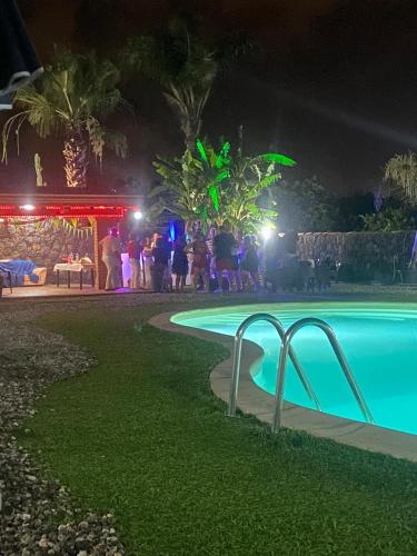 a group of people standing around a pool at night at Il Rustico in Pozzillo