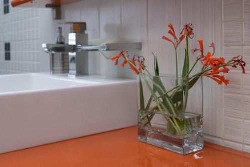 ALBJONA GUESTHOUSE TIRANA في تيرانا: مزهرية زجاجية مع زهور برتقالية على طاولة