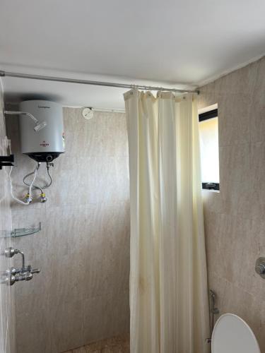 a bathroom with a shower curtain and a toilet at The Nautical Nest - Para House in Canacona