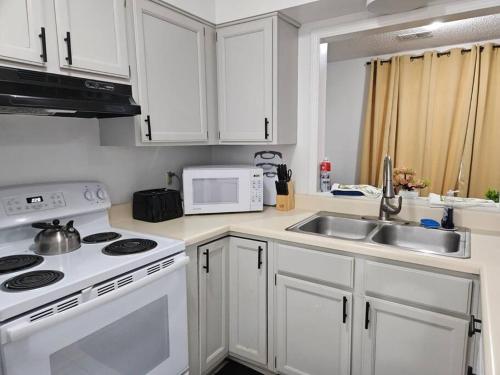 a kitchen with white cabinets and a sink and a microwave at Cozy Bartlett home with garage, fenced backyard in Memphis