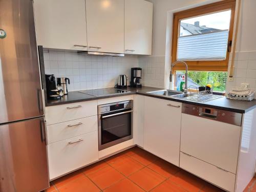 eine Küche mit weißen Schränken, einem Waschbecken und einem Fenster in der Unterkunft Ferienhaus Heckler in Bad Camberg