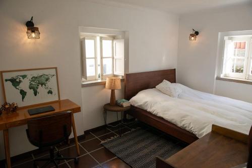 a bedroom with a bed and a desk and two windows at Private Terrace Refúgio in Sesimbra