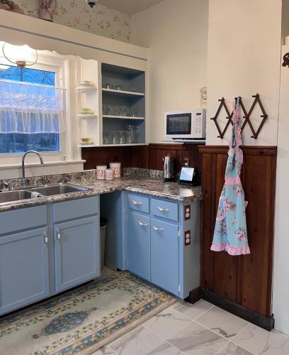 a kitchen with blue cabinets and a dress hanging on the wall at Sandbank Cottage in Creal Springs