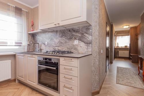 a kitchen with white cabinets and a stove top oven at Feel like home Apartment SELF CHECK IN in Klaipėda