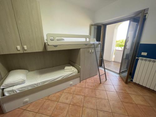 a small room with a bunk bed and a window at Villa Lidia & Attico degli artisti, free pets , giardino recintato e attrezzato in Minturno