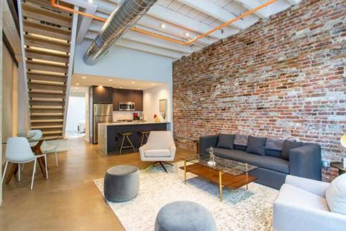a living room with a couch and a brick wall at Inventors' Loft - Stay in the Heart of it All in Philadelphia