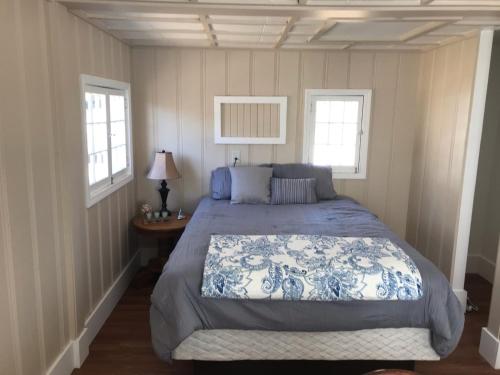 um quarto com uma cama e duas janelas em Lakeshore Cabin 2 dock, boat slip and patio em Lake Ozark