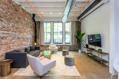 a living room with a couch and a brick wall at Inventors' Loft - Stay in the Heart of it All in Philadelphia