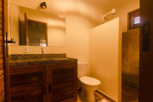 a bathroom with a toilet and a sink and a mirror at Vila Flamboyant in Barra Grande