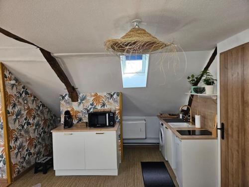 eine Küche mit weißen Schränken, einem Waschbecken und einem Fenster in der Unterkunft RÃªve de Loire in La Daguenière