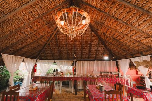 una sala da pranzo con lampadario pendente, tavoli e sedie di Pousada Vitória do Lopes a Barreirinhas