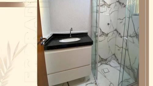 a bathroom with a sink and a glass shower at apartamento de ferias na praia em sao paulo [peruibe],rua joao atalla,280 estancia balneria Maria Helena Novais in Peruíbe