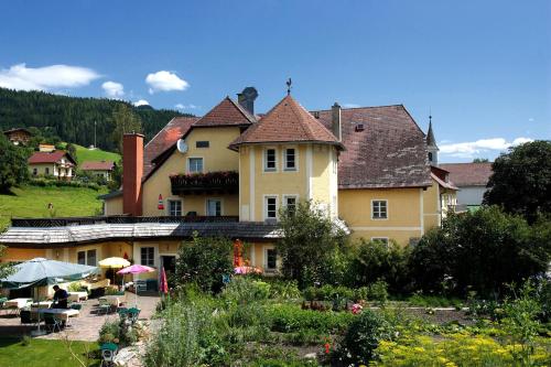 Una gran casa amarilla con un jardín enfrente. en Landhotel Restaurant Hubinger, en Thörl
