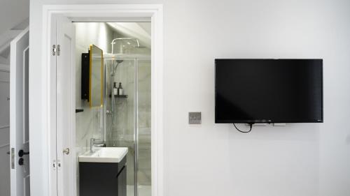 a bathroom with a tv on a wall next to a sink at Oakleigh House, 3 bedroom, free parking in East Barnet