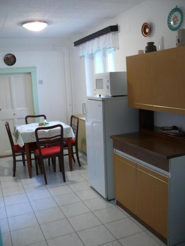 a kitchen with a table and chairs and a kitchen with a table and a kitchen at Madácsi Vendégház in Kiskőrös