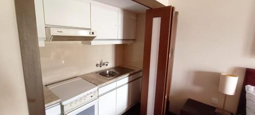uma pequena cozinha com armários brancos e um lavatório em Apartamento Villa Galé Cascais em Cascais