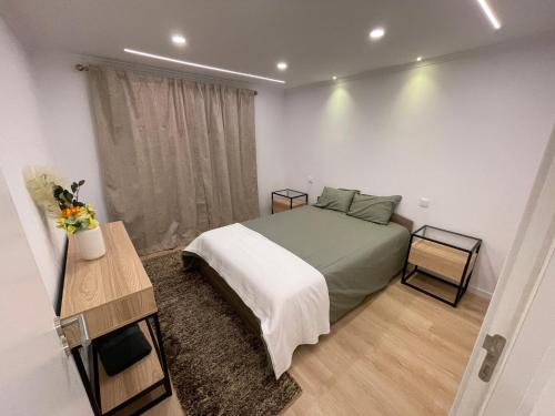 a bedroom with a bed and a table and a window at Neto Pinto - Casa de férias / fins de semana. in Lourinhã