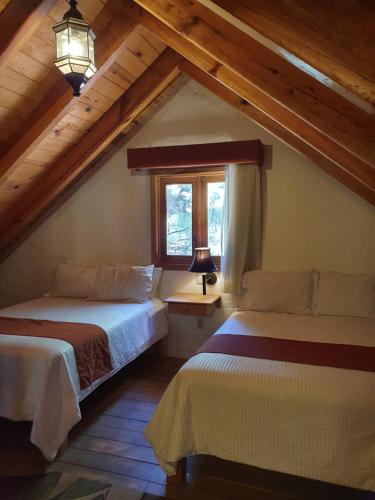a attic bedroom with two beds and a window at Cabañas Sierra Mazamitla in Mazamitla