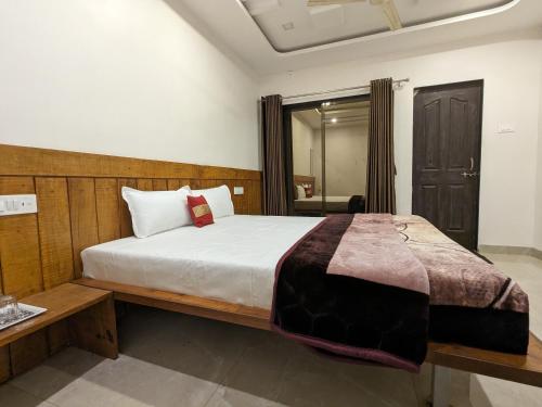 a bedroom with a large bed with a wooden headboard at Hotel and Villa Samarth Palace in Panchgani