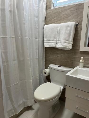 uma casa de banho com um WC branco e um lavatório. em Posada Centric Studio Isla Verde em San Juan