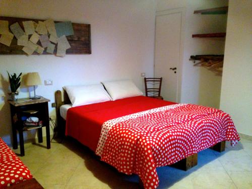 Schlafzimmer mit einem Bett mit einer roten und weißen Decke in der Unterkunft C'era una volta in Asciano