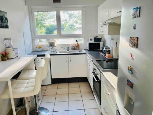 une cuisine avec des armoires blanches, un évier et une fenêtre dans l'établissement FELINE’S Appart - T2 Moderne 51 m2, proche centre, à Poitiers