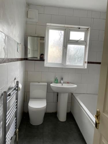 a bathroom with a toilet and a sink and a window at Dudley court, Lower Road in Harrow on the Hill