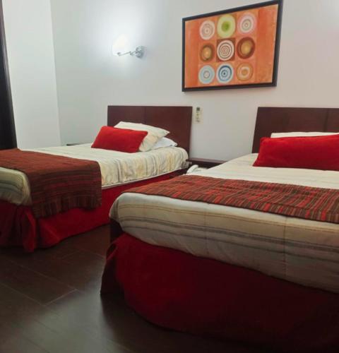 two beds with red pillows in a room at HBCF Hotel Boutique Casa Farallones de Santiago de Cali in Cali