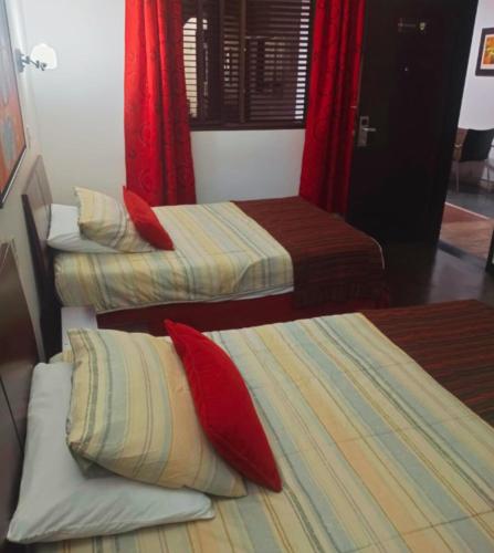 three beds in a room with red curtains at HBCF Hotel Boutique Casa Farallones de Santiago de Cali in Cali