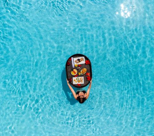 a person on a paddle board in a pool of water at Golden Rock Dive and Nature Resort in Oranjestad