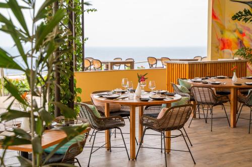a restaurant with tables and chairs with the ocean in the background at Golden Rock Dive and Nature Resort in Oranjestad
