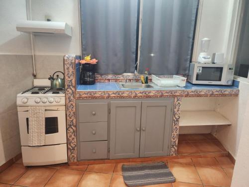 a kitchen with a counter with a sink and a stove at 1 BR APT with AC , TV , wi-fi near DT and beach in Zihuatanejo