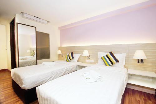 a hotel room with two beds and a mirror at Good Luck Inn in Ayer Itam