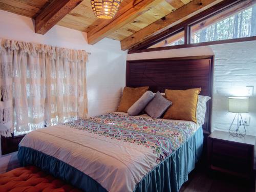 a bedroom with a large bed in a room with windows at BACANA CABAÑAS DE ALQUILER in Mazamitla