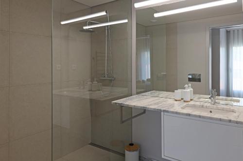 een badkamer met een douche, een wastafel en een spiegel bij FLH Boavista Woody Duplexes in Porto