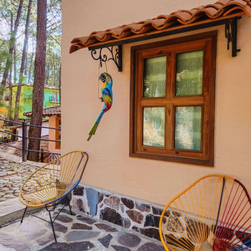 a colorful bird on the side of a building with two chairs at BACANA CABAÑAS DE ALQUILER in Mazamitla
