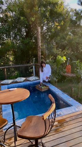 uma mulher ao lado de uma piscina com uma mesa em Refúgio prox Ctba Chalé Suíço 50m2, 400 m2 de área em Mandirituba