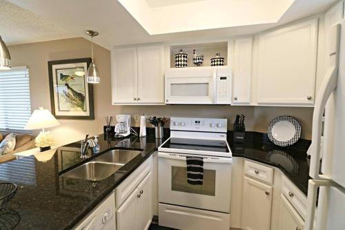 a kitchen with white cabinets and a stove and a sink at Beach Side complex B23 1 Bed 1 Bath w/Heated Pool in Saint Augustine