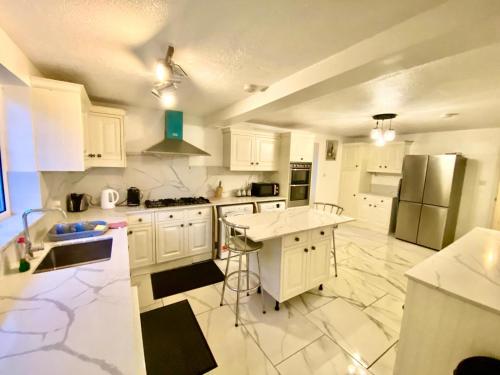 a kitchen with white cabinets and stainless steel appliances at Luxury Large Four Bedroom Family House in Luton