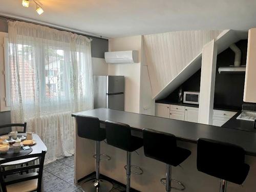 a kitchen with a black counter and black bar stools at Cosy apartment proche Paris et Disneyland in Gagny